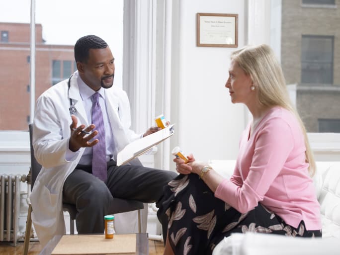 Doctor Discussing Medication with his patient as they sit next to one another