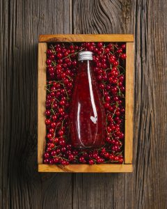 cranberry juice sitting in a bed of cranberries in a wooden box