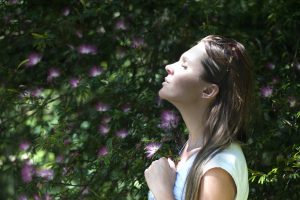 Woman outside breathing in the fresh air and practicing staying optimistic.