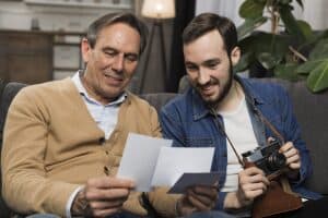 father and adult son looking at pictures as son holds a camera, happy after prostatic artery embolization (PAE) to relieve urinary incontinence