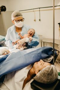 mother looking at newborn in nurse's arms right after birth
