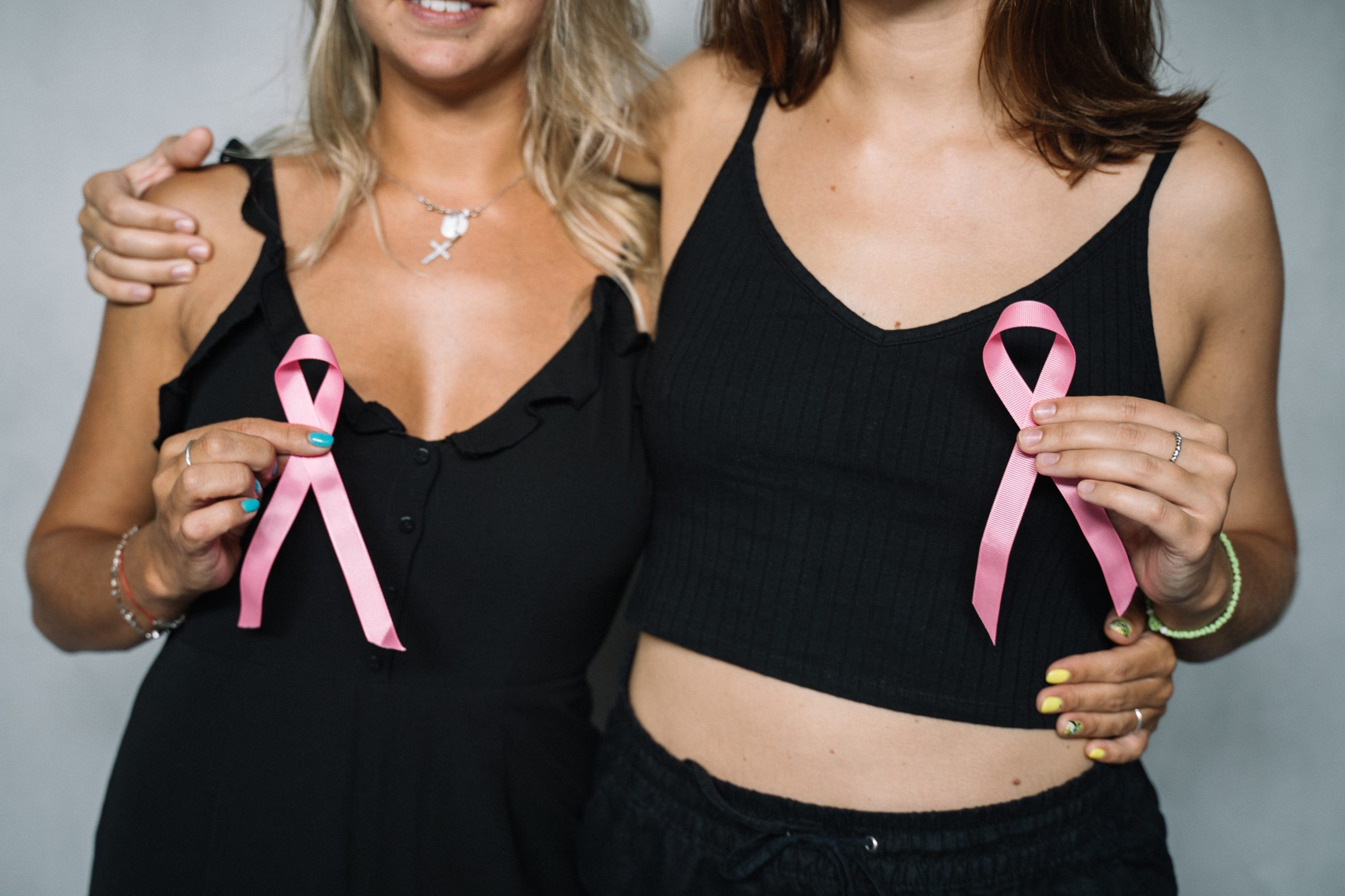 two women holding pink ribbons showing their support of breast cancer screenings