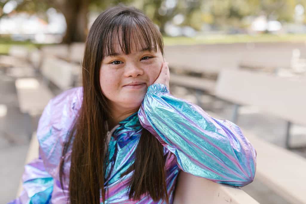 girl with down syndrome sitting on a bench