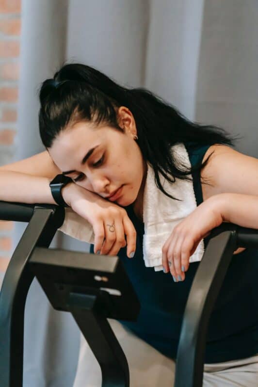 woman feeling fatigued on an exercise machine