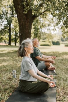 older woman and man doing yoga in a park