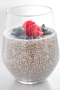 chia pudding in a glass with raspberries and blueberries can help with irritable bowel syndrome symptoms and gluten intolerance